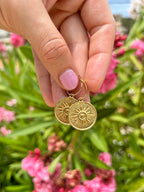 24k Gold Plated Brass Coin Mini Hoops displayed against pink flowers, featuring intricate sun-ray design medallions on delicate hoops. Elegant boho-style earrings shown with pink manicured nails. By Aloë Earrings - Collections: Jewellery, Gifts Under £15, Gifts under £20, Earrings, Face, Aloe Earrings