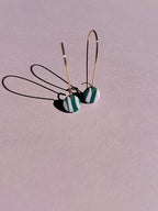 24k Gold Plated Mini Pink & Green Wavy Oval Hoops featuring delicate 30mm oval hoops with 9mm clay discs in wavy green and pastel pink stripes, casting elegant shadows on pink background. By Aloë Earrings - Jewellery, Gifts Under £15, Gifts under £20, Earrings, Face, Aloe Earrings