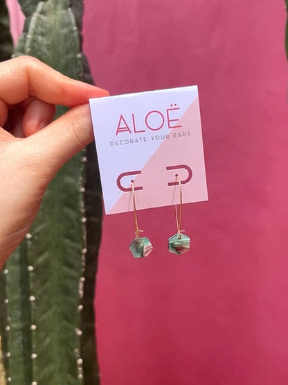 24k Gold Plated Mini Hex Oval Hoop Earrings displayed on white brand card featuring marbled green and purple hexagon charms suspended from delicate oval hoops against pink background with cactus detail - by Aloe Earrings | Jewellery, Gifts Under £15, Gifts under £20, Earrings, Face, Aloe Earrings