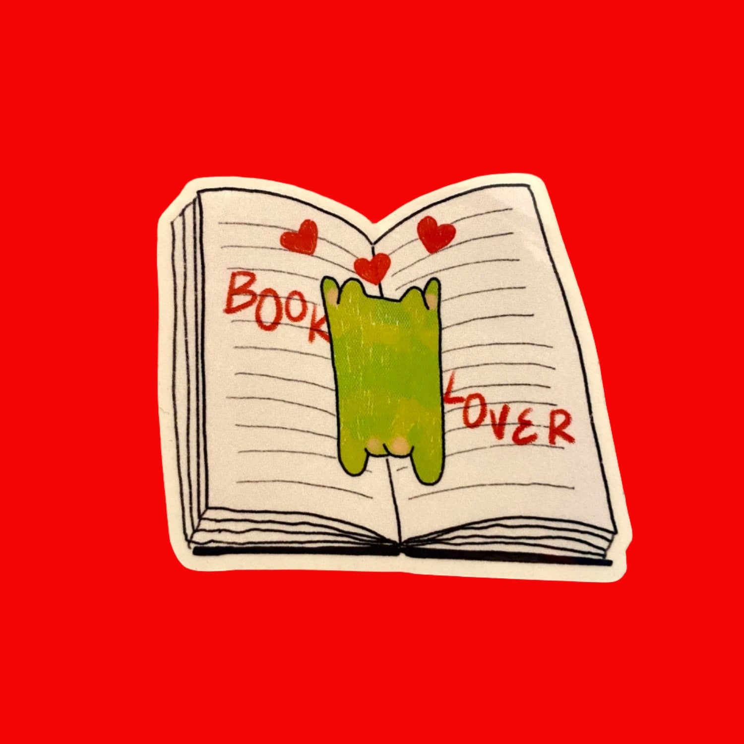 A cute green frog sprawled across an open book sticker