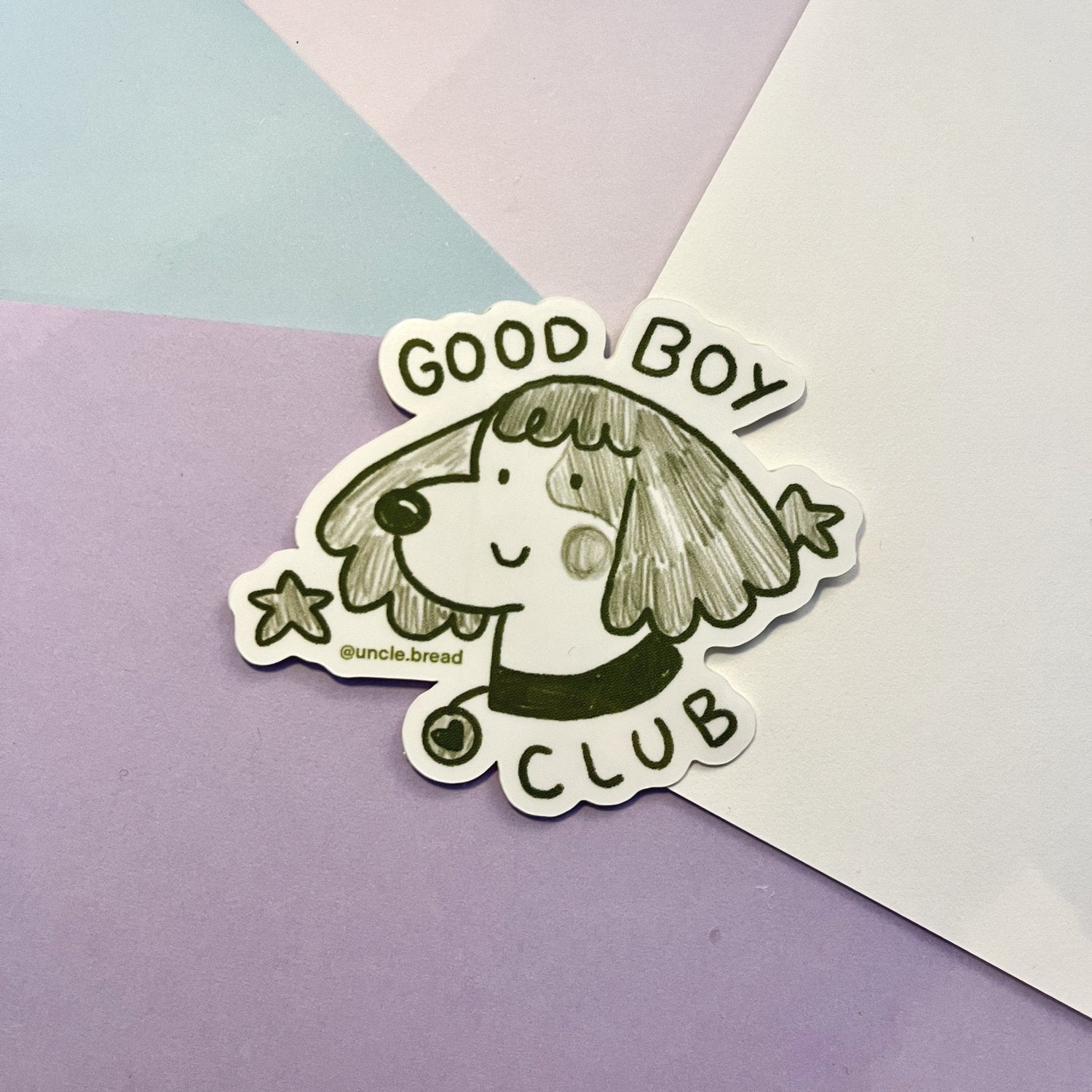 Cute cartoon dog sticker with smiling face and floppy ears, featuring text Good Boy Club. White vinyl design with black outline on pastel background. Good Boy Club Dog by Uncle Bread's Art Club - Stickers Collection, Face Collection.
