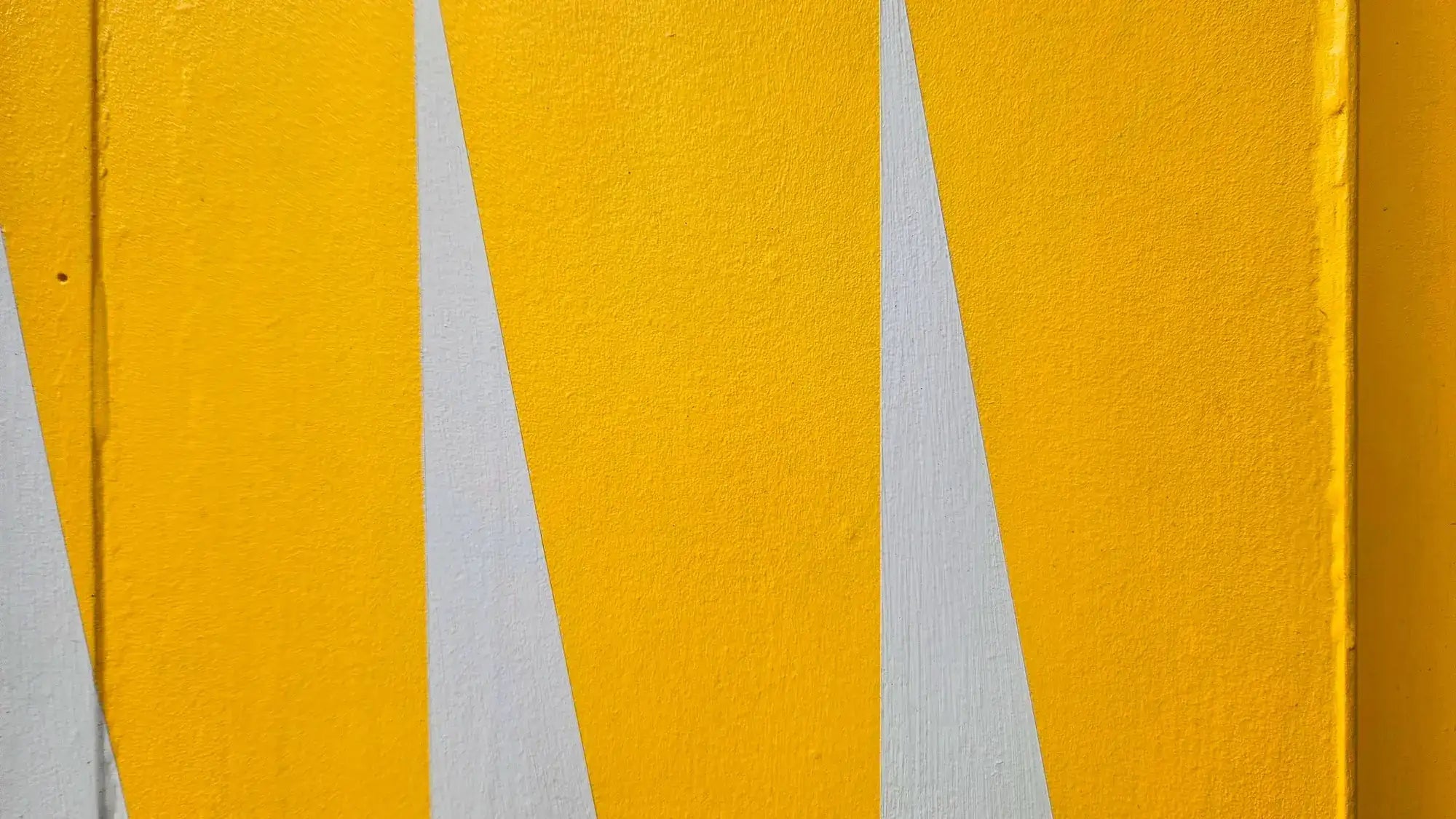 Close-up of the Neighbourhood Store front door surround, showing bold yellow geometric painted panels by artist Chloe Batchelor