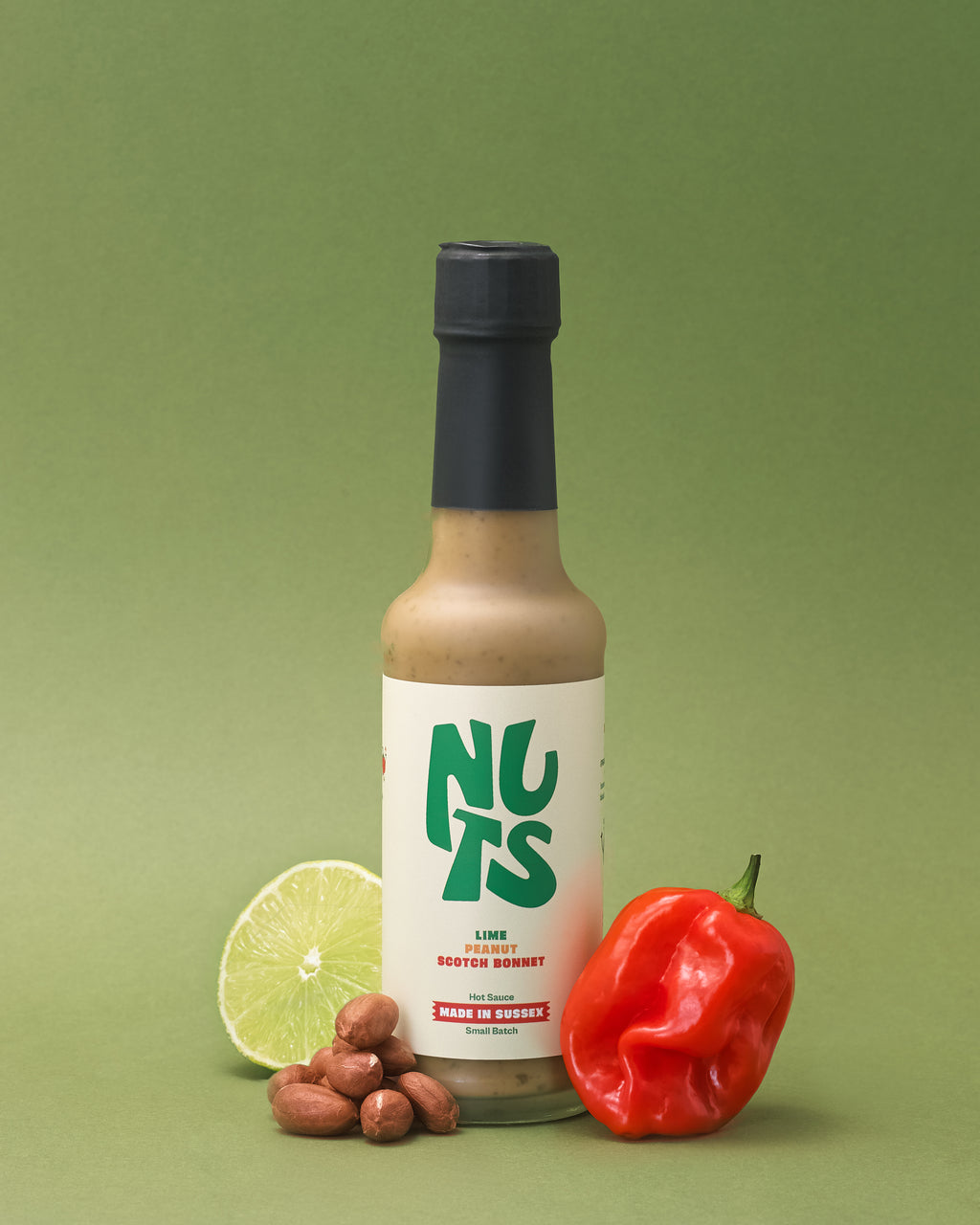 Bottle of Nuts Hot Sauce with nuts, a hot chili and a lime